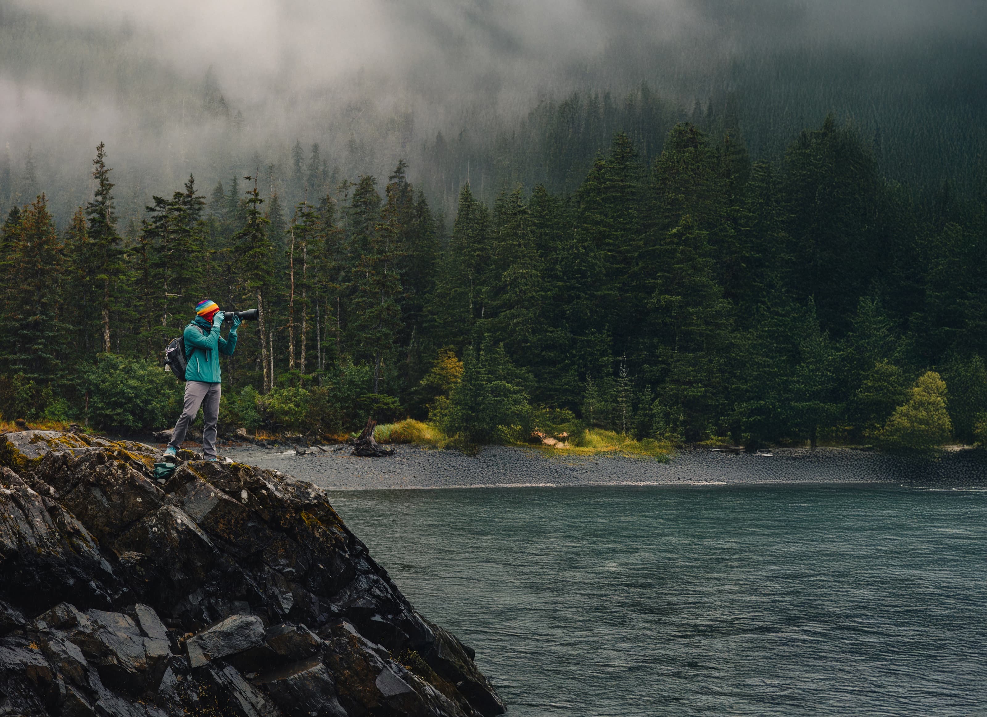 Travel photographer working in a misty Alaska forest